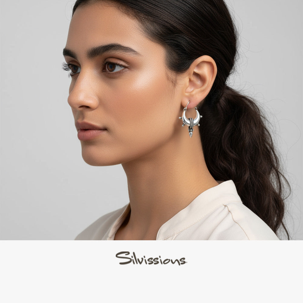 Woman wearing silver hoop earrings with a neutral background, featuring the brand 'Silvissions'.