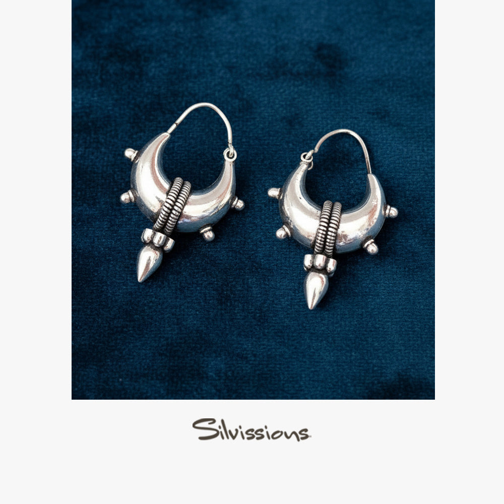 Silver earrings with a unique design on a blue background, branded 'Silvissions'.