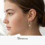 Close-up of a woman wearing a silver hoop earring with a heart charm, branded 'Silvassions'.