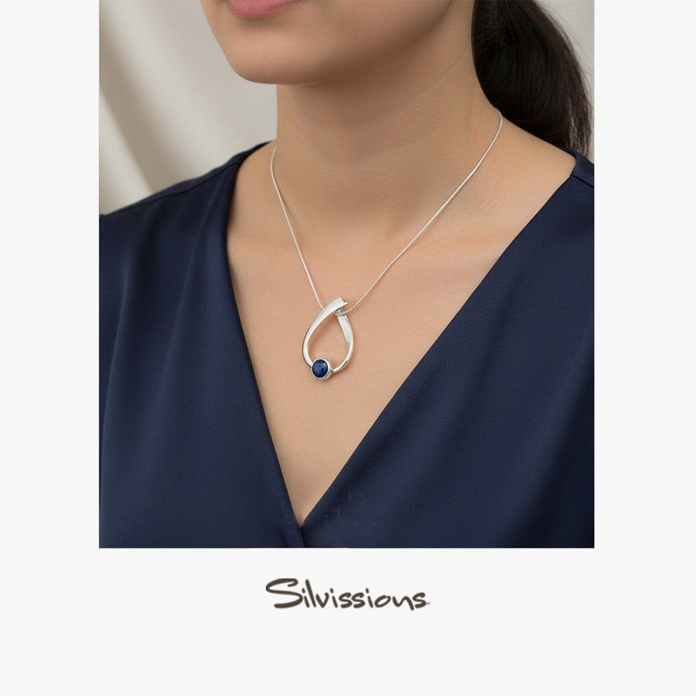 Silver necklace with a blue pendant worn by a person, branded 'Silvissions'.