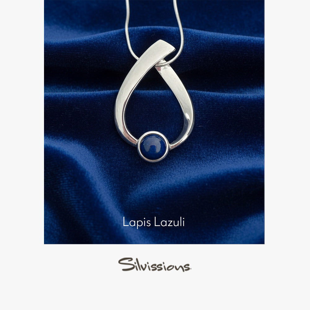 Silver pendant with a blue gemstone on a blue fabric background, featuring the brand 'Silvissions'.