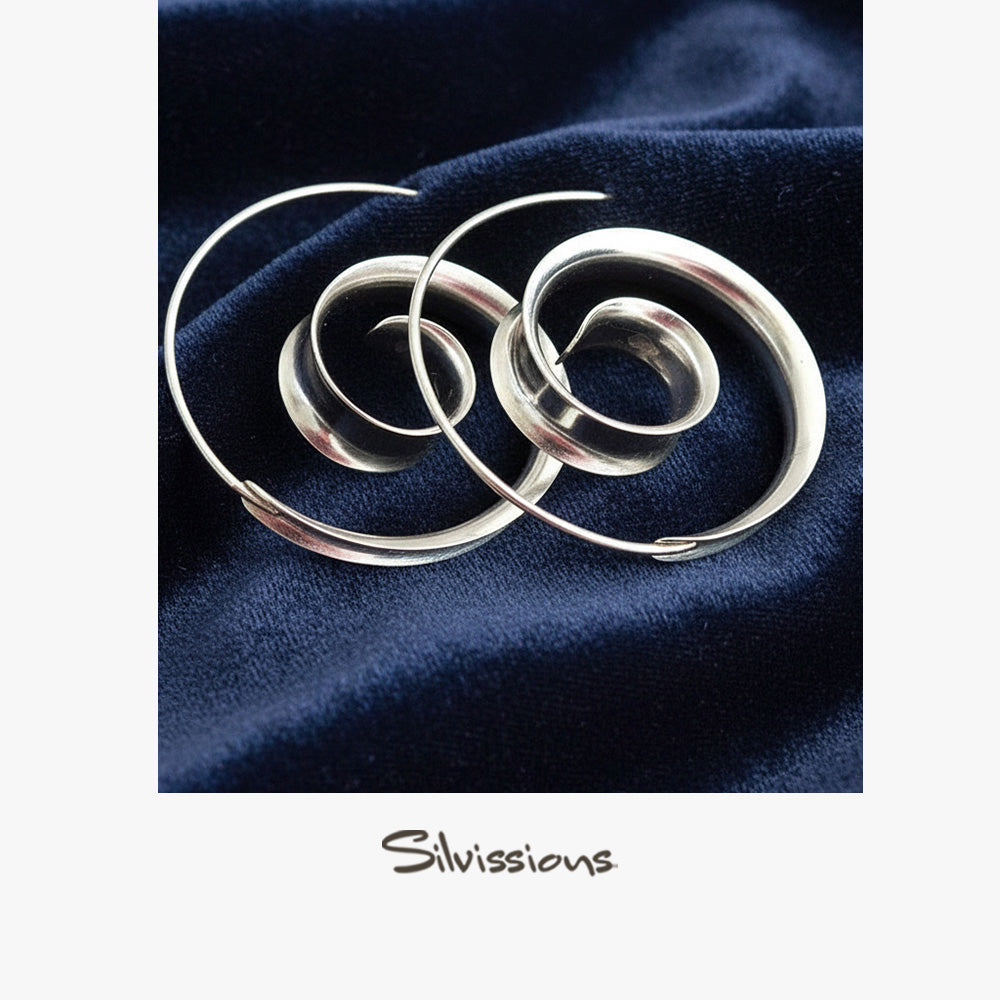 Silver circular earrings on a dark blue fabric background with 'Silvissions' branding.
