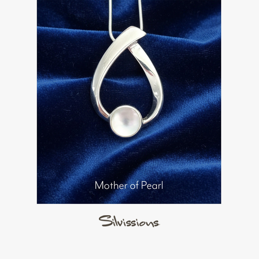 Silver pendant with a mother of pearl on a blue satin background, branded 'Silvissions'.