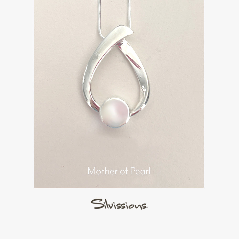 Silver pendant with a mother of pearl on a beige background, featuring the brand 'Silvissions'.