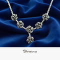 Silver rose necklace on a blue fabric background with 'Silvissions' branding.