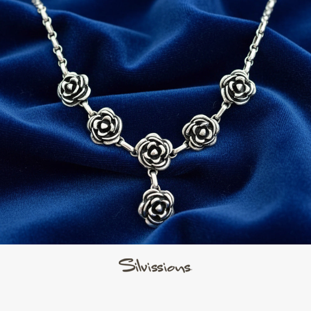 Silver rose necklace on a blue fabric background with 'Silvissions' branding.