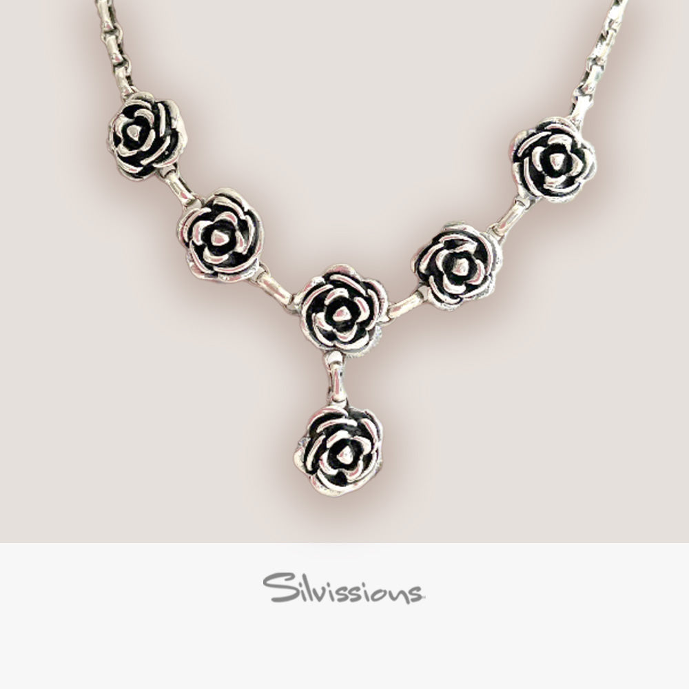 Silver necklace with rose-shaped pendants on a light background, featuring the brand 'Silvissions'.