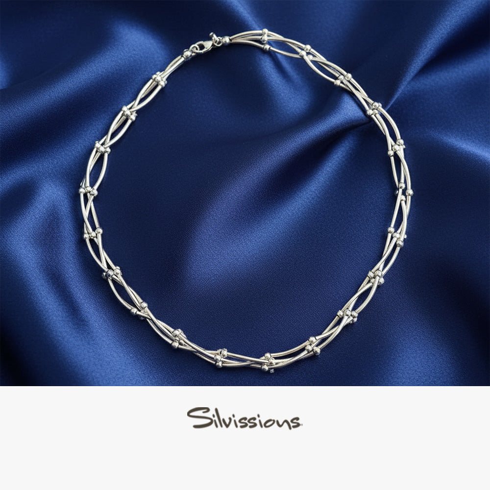 A sterling silver necklace with a chain link design, on blue silky background.