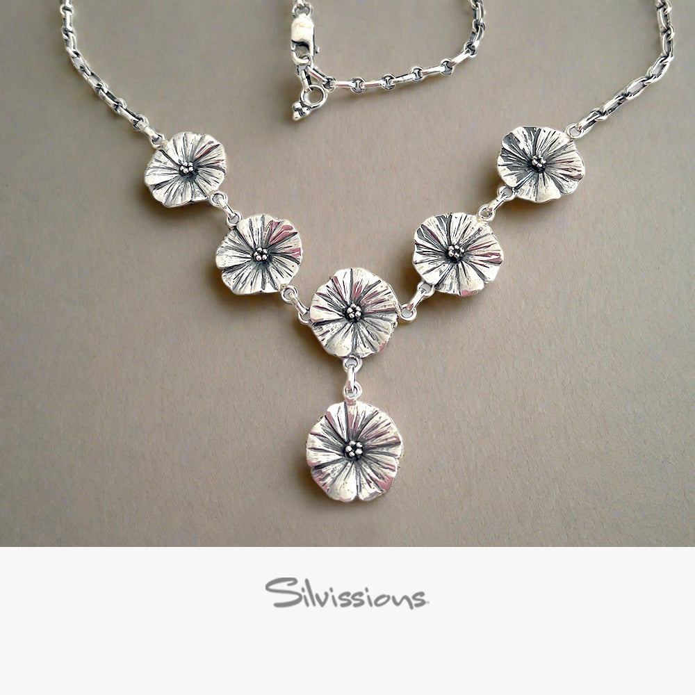 Silver necklace with floral designs on a neutral background, featuring the Silvissions Jewelry brand.