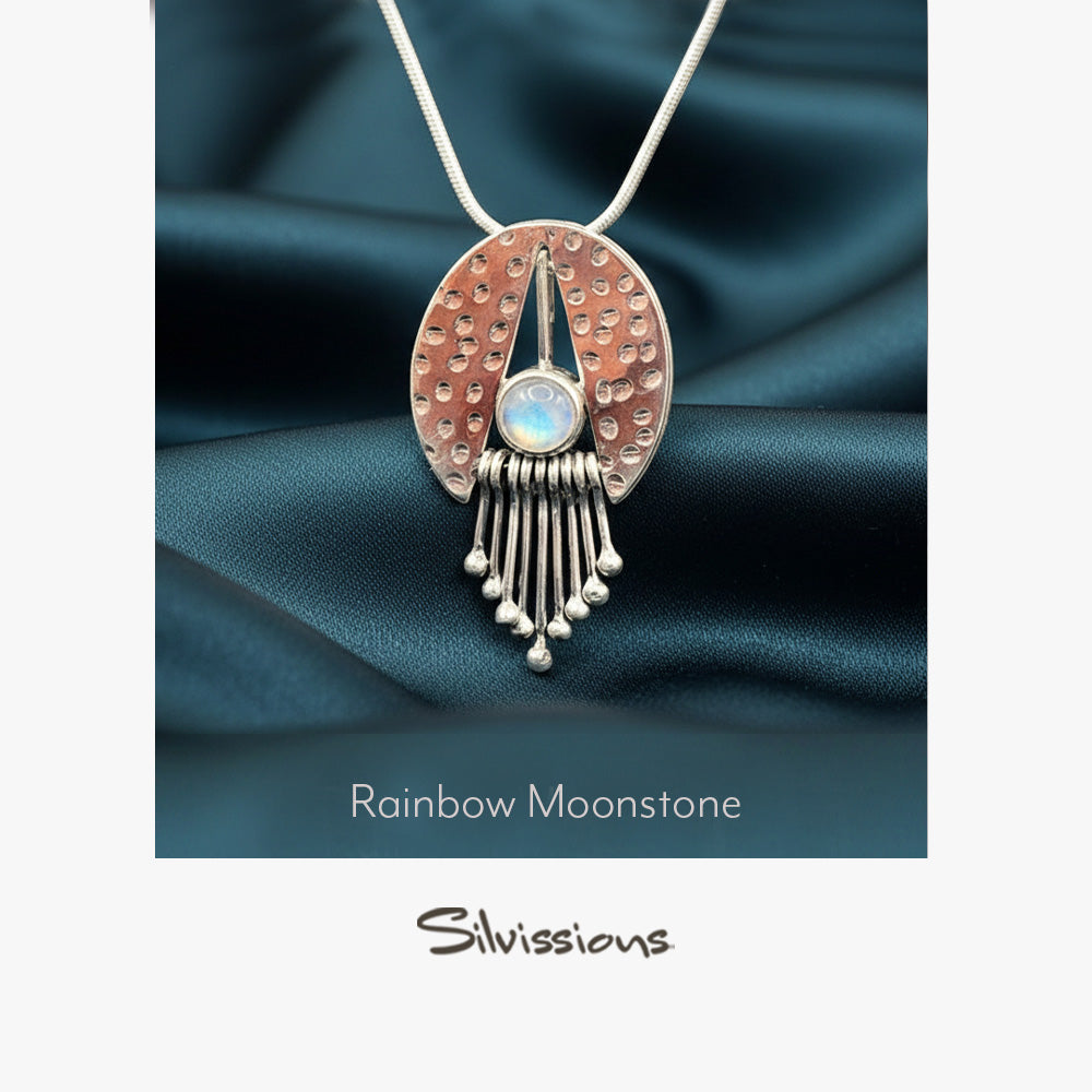 Silver pendant with rainbow moonstone on a dark fabric background, featuring the brand 'Silvissions'.