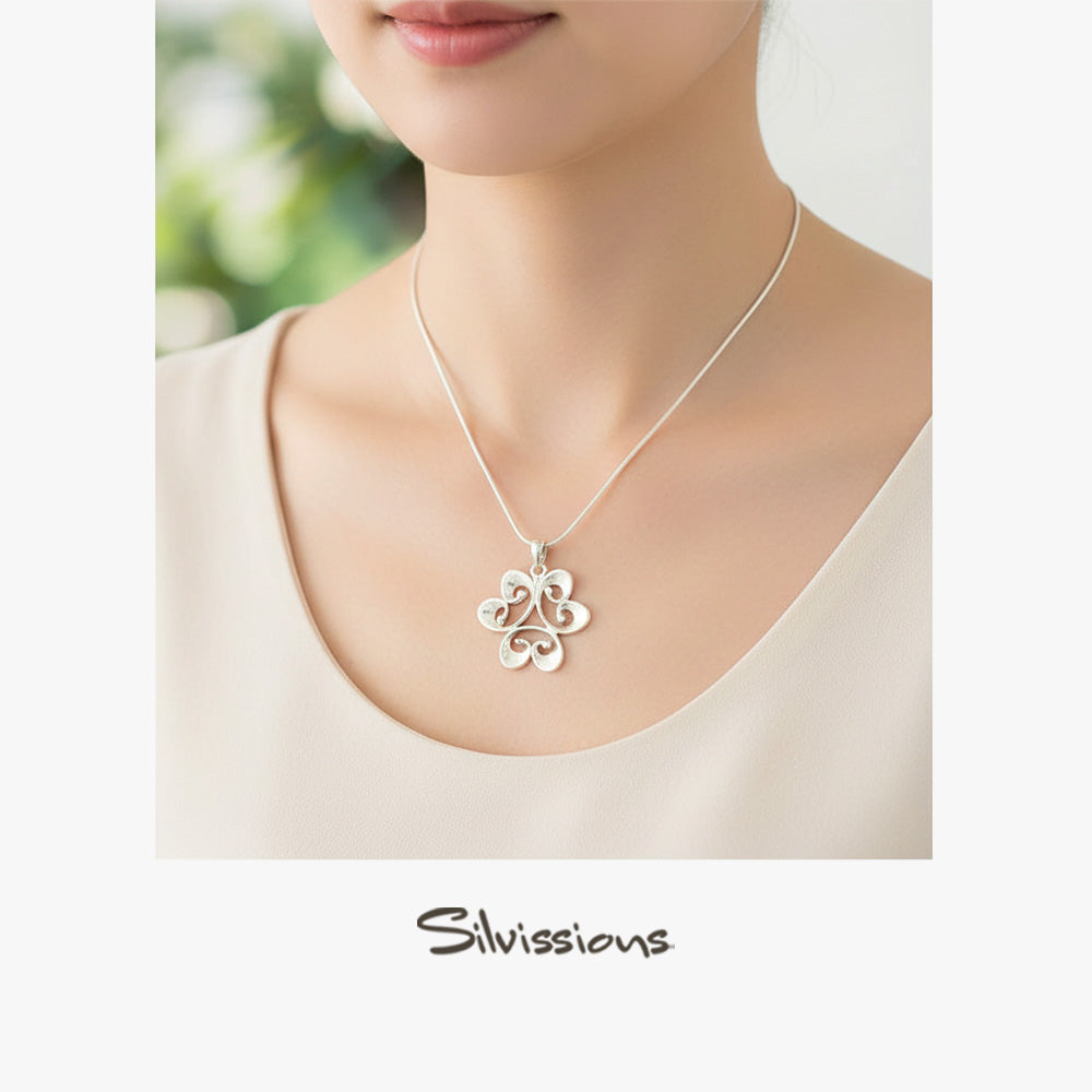 Silver necklace with a floral pendant worn by a person, brand 'Silvissions' visible