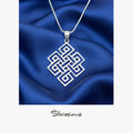 Silver necklace with a geometric pendant on blue satin fabric, branded 'Silvissions'.