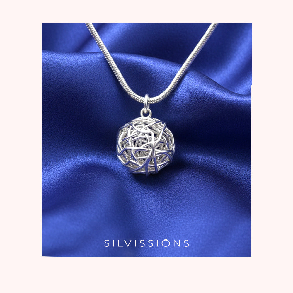 Silver necklace with a spherical pendant on a blue satin background, featuring the brand 'Silvissions'.