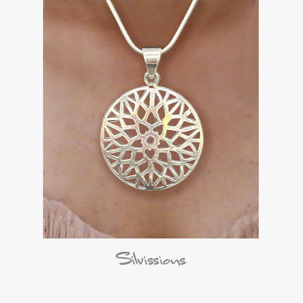 A handcrafted pendant necklace in sterling silver with a intricate geometric design, suspended on a silver rope chain around a mannequin's neck.