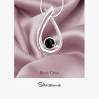 Silver pendant with black onyx stone on pink satin fabric, featuring the brand 'Silvissions'.