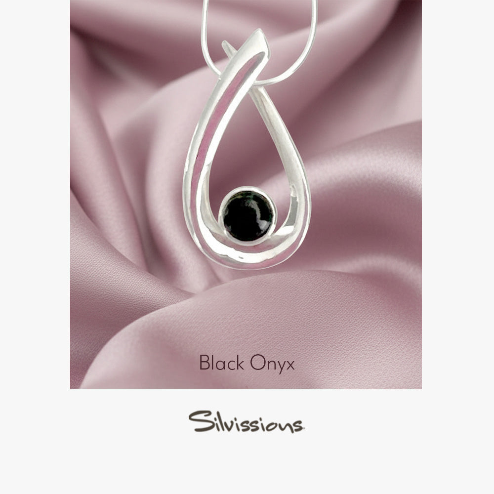 Silver pendant with black onyx stone on pink satin fabric, featuring the brand 'Silvissions'.