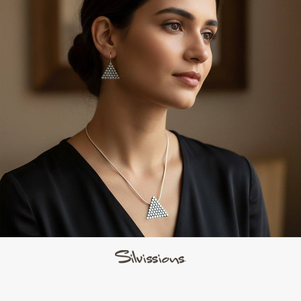 Woman wearing triangle-shaped earrings and necklace with 'Silvissions' branding.
