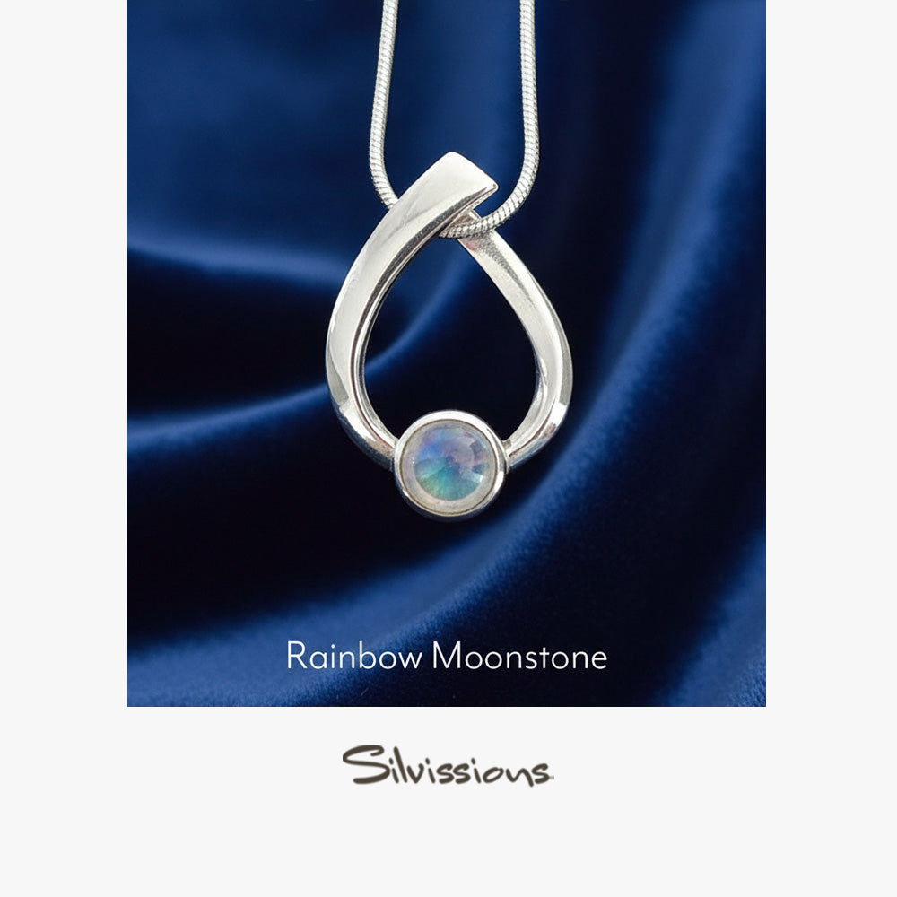 Silver pendant with rainbow moonstone on a blue satin background, featuring the brand 'Silvions'.