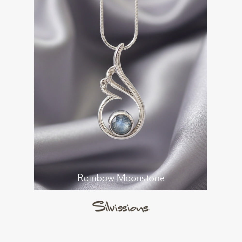 Silver pendant with rainbow moonstone gemstone on a blue background, featuring Silvissions Jewelry branding.