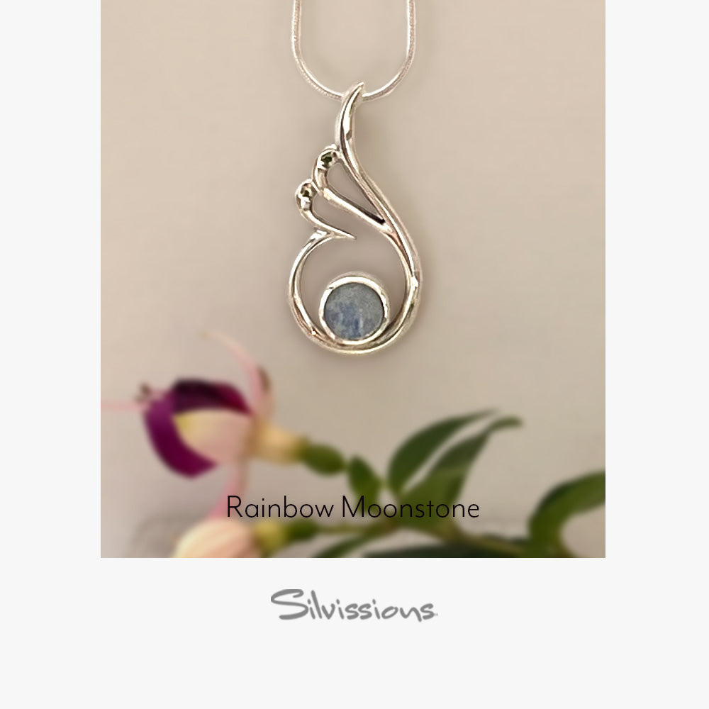 Silver pendant with rainbow moonstone gemstone on a blue background, featuring Silvissions Jewelry branding.