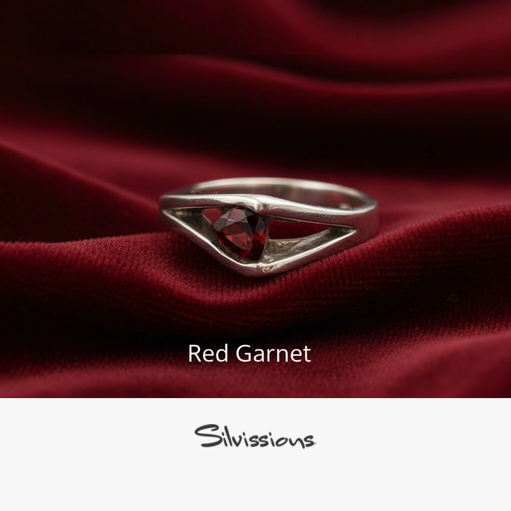 Silver ring with a red garnet stone on red fabric, branded 'Silvissions'.