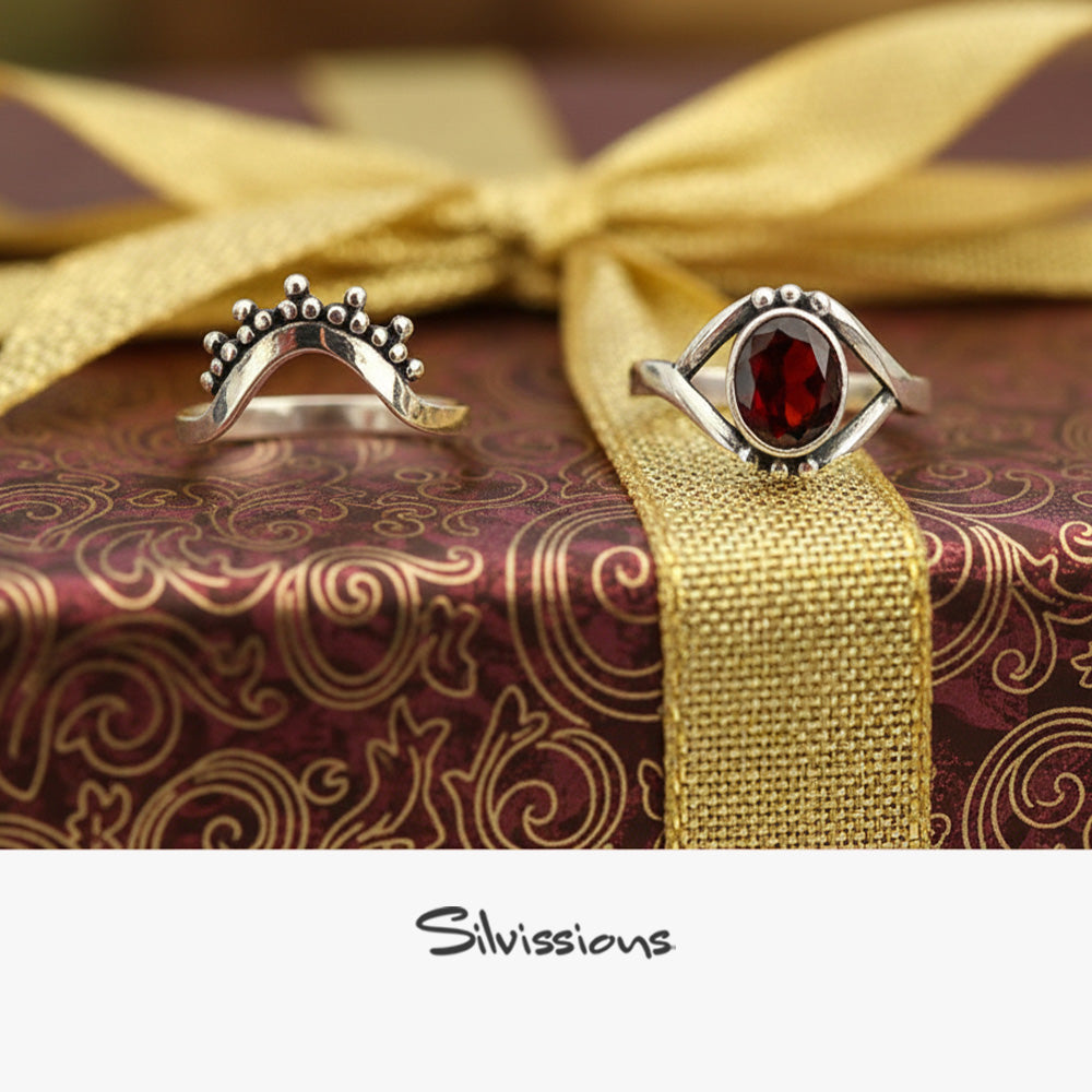 Two silver rings with gemstones on a decorative box with gold ribbon, featuring the brand 'Silvissions'.
