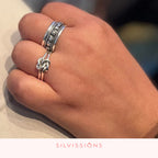 Close-up of a hand wearing two silver rings with 'Silvissions' branding.