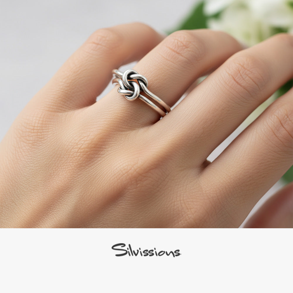 Silver knot ring on a hand with 'Silvassions' branding.