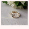 Silver knot ring on a light background with 'Silvissions' branding