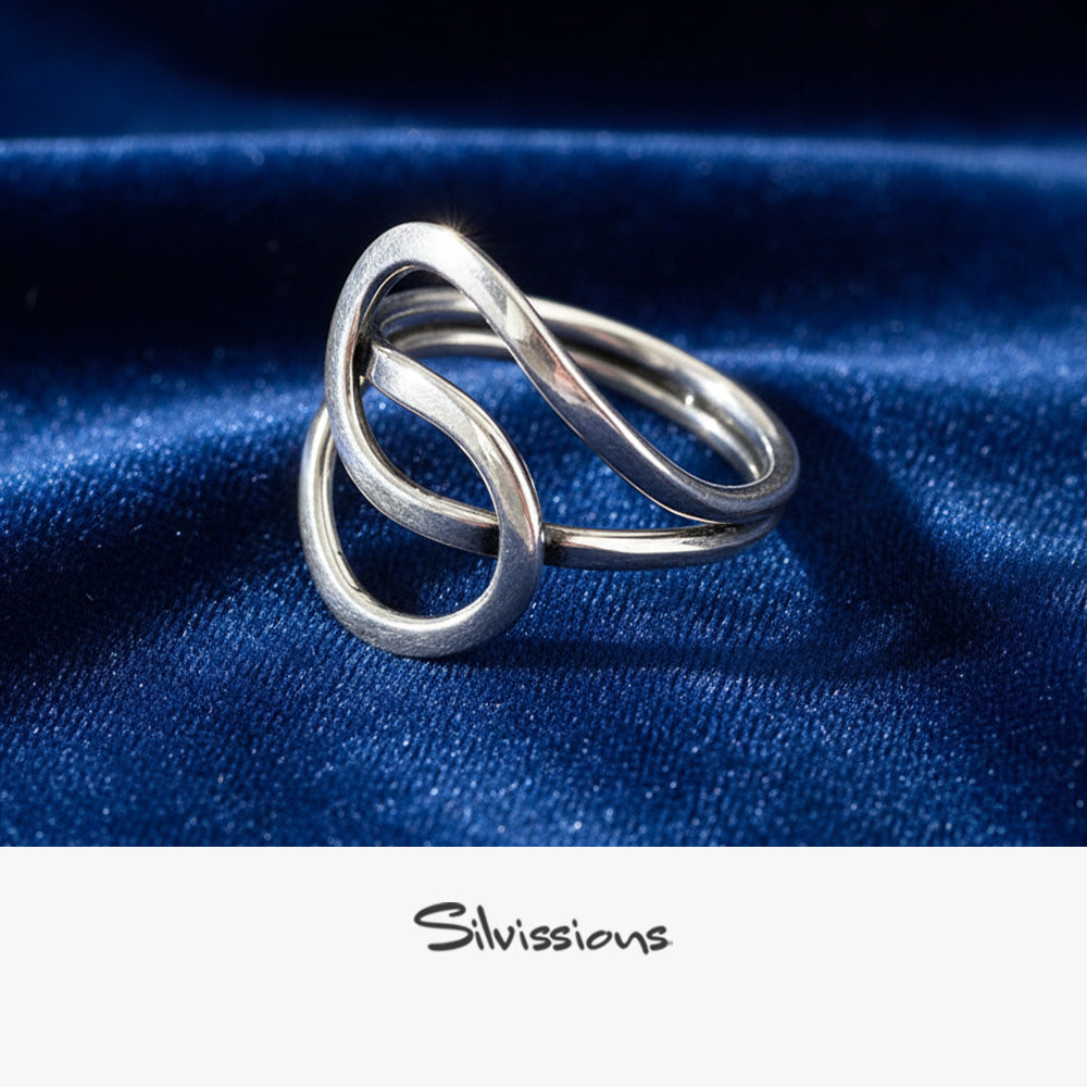 Silver ring with interlocking loops on a blue fabric background, featuring the brand 'Silvissions'.