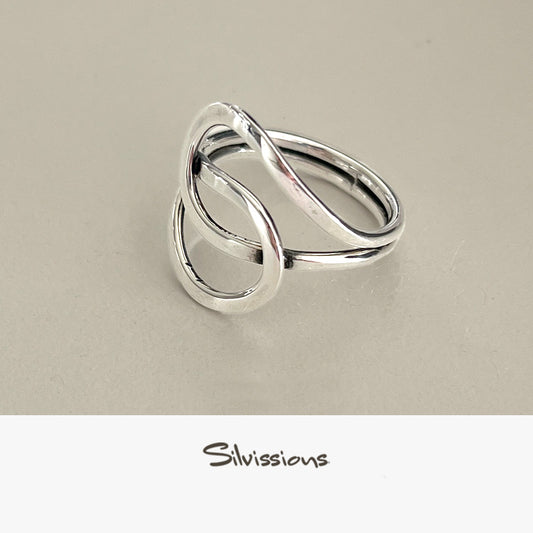 A sterling silver ring with an intricate endless knot design, displayed on a light background with a text mentioning the artisan jewelry crafted with genuine sterling silver and gemstones.