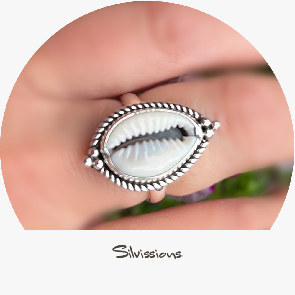 Silver ring with a shell inlay on a hand against a blurred natural background