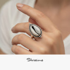 Silver ring with a cowrie shell on a hand, branded 'Silvissions'.