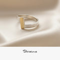 Silver ring with a gold accent on a beige fabric background, featuring the brand 'Silvissions'.