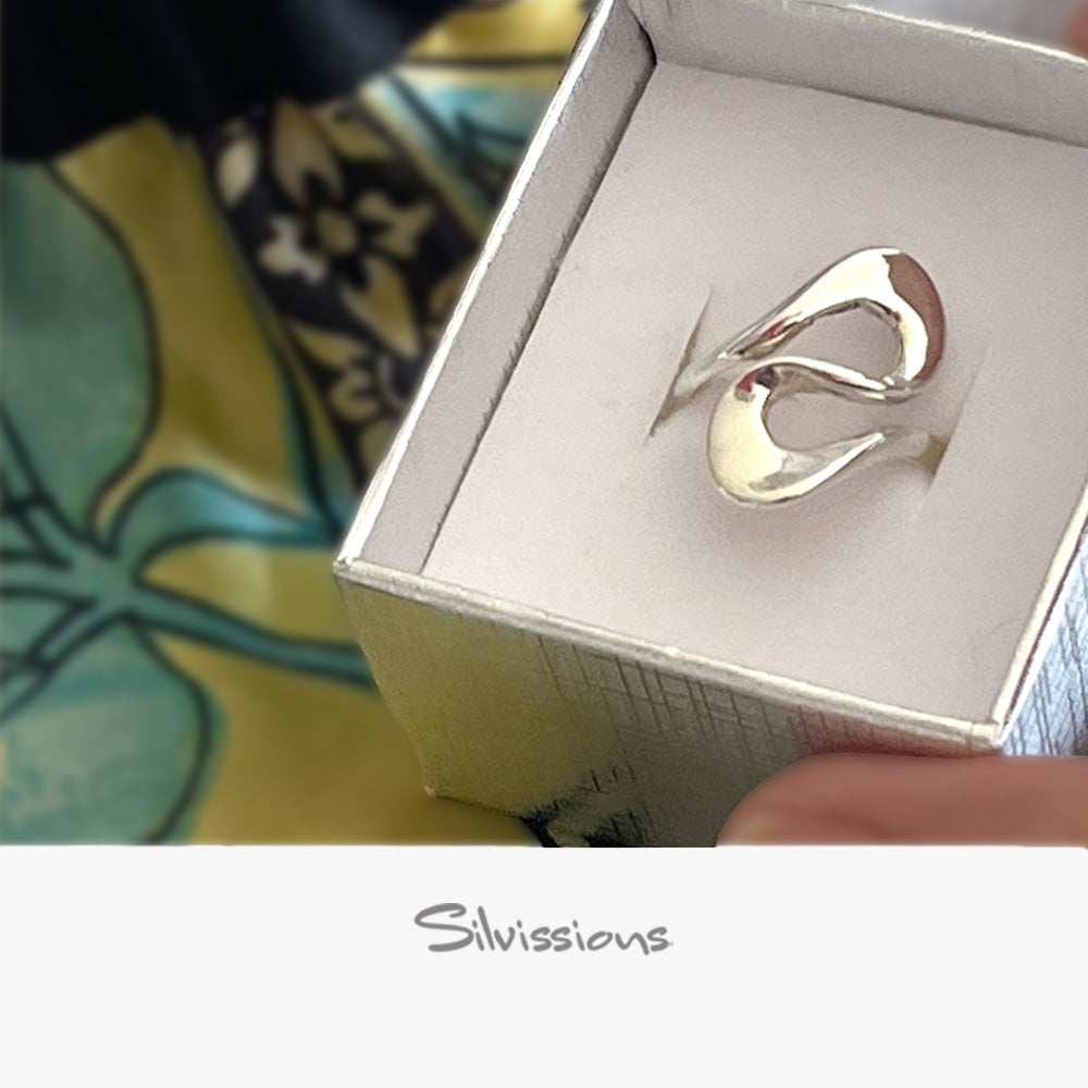 Silver ring in a box with 'Silvissions' branding on a colorful fabric background
