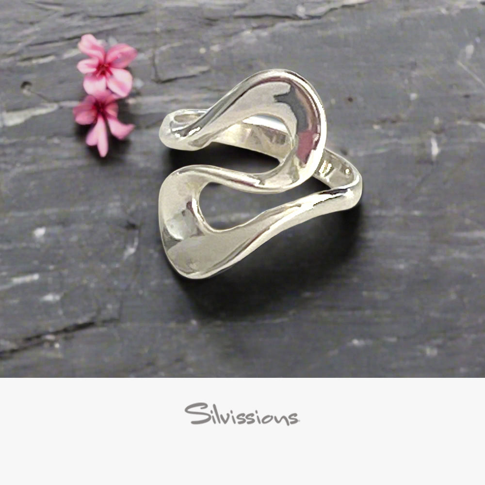 Silver ring on a dark stone surface with a pink flower