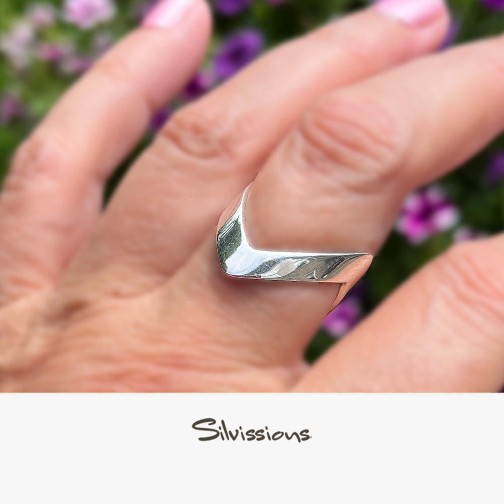 Silver ring on a hand with a blurred floral background, featuring the brand 'Silvissions'.