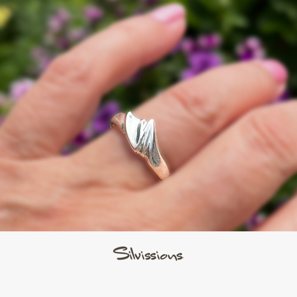 Silver ring with a wavy design on a finger, branded 'Silvissions'.