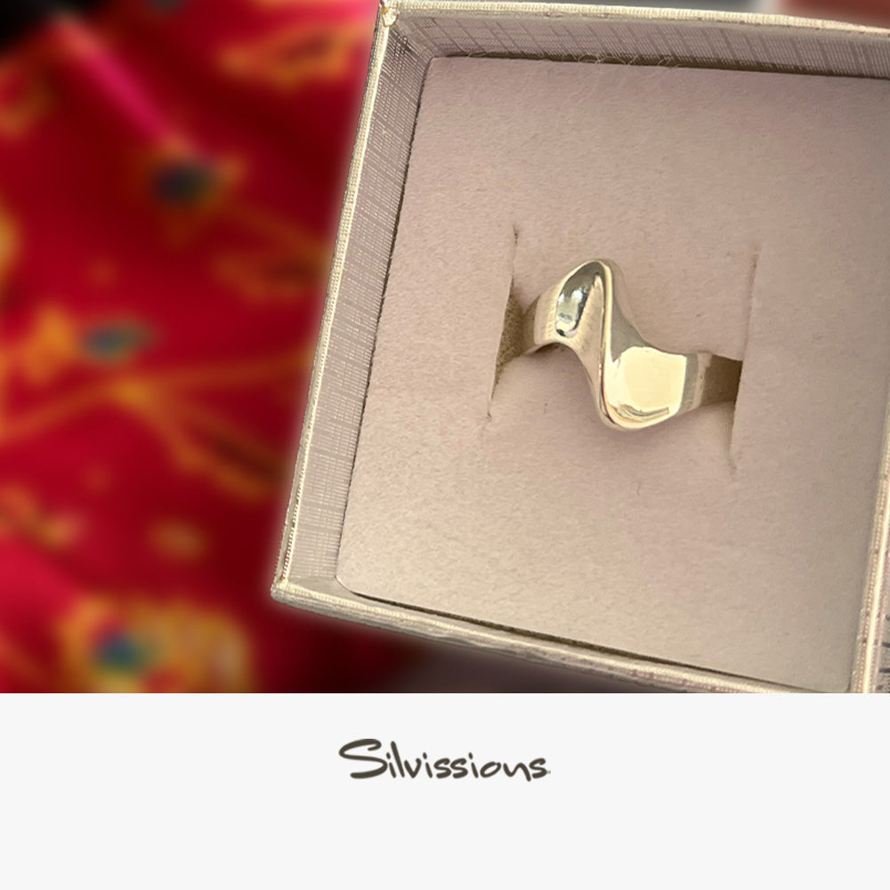 Silver ring in a box, branded 'Silvissions', on a colourful fabric background.