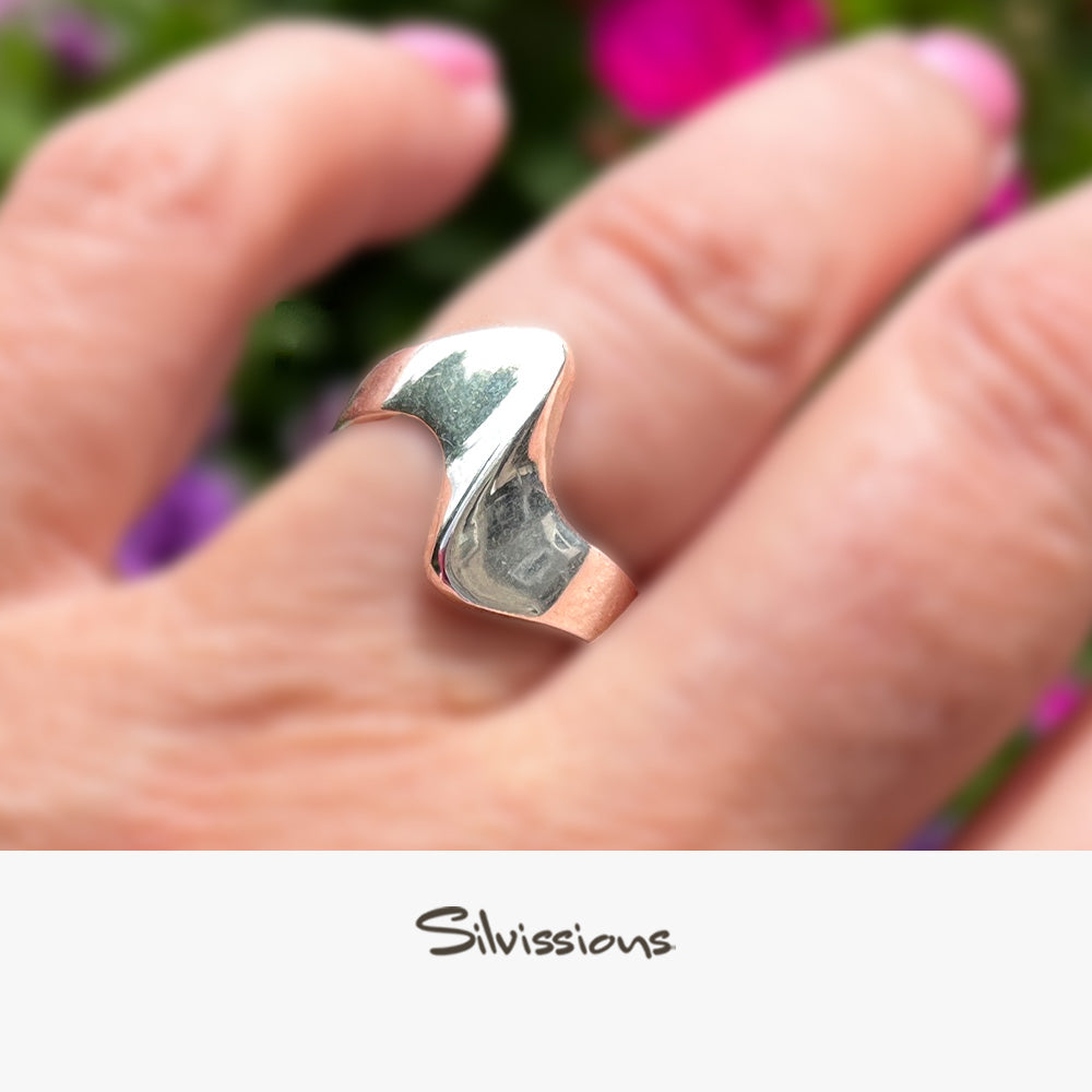 Silver ring on a hand with a blurred floral background, featuring the brand 'Silvissions'.
