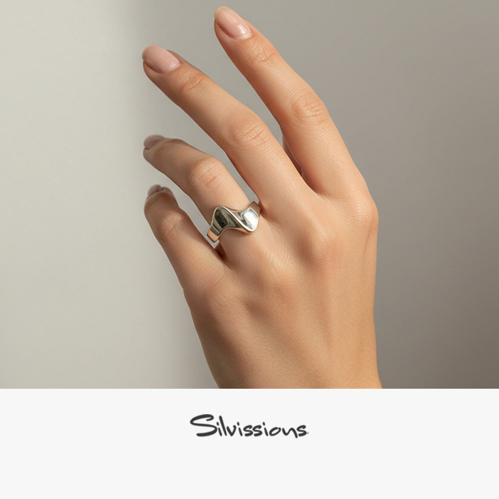 Hand wearing a silver ring on a neutral background, featuring the brand 'Silvissions'.