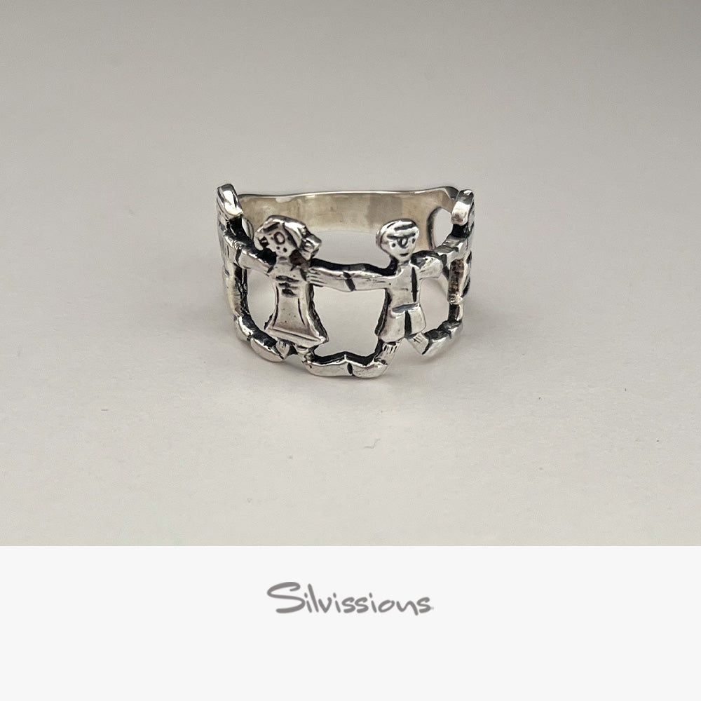 Silver ring with a design of four family members holding hands on a light gray background, branded 'Silvissions'.