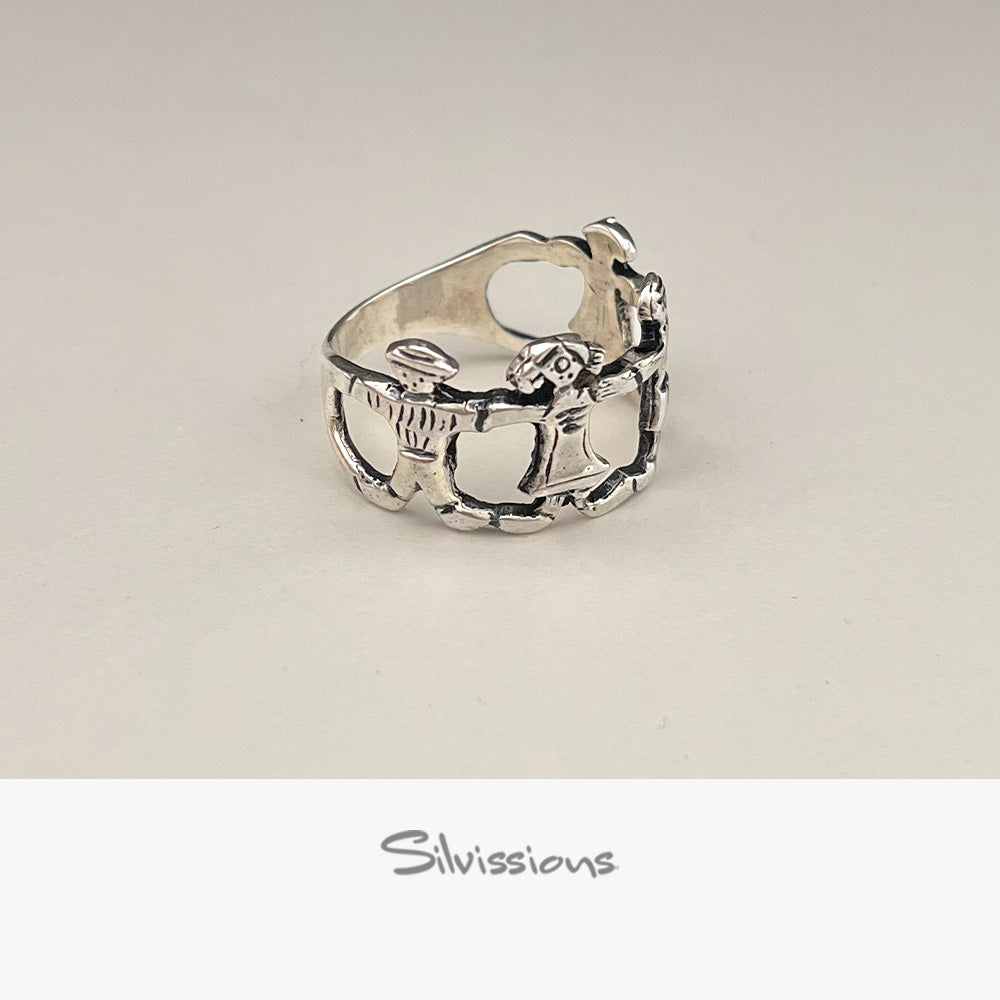 Silver ring with intricate family design on a light beige background, branded 'Silvissions'.