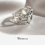 Silver ring with intricate family design on a light gray background, branded 'Silvissions'.