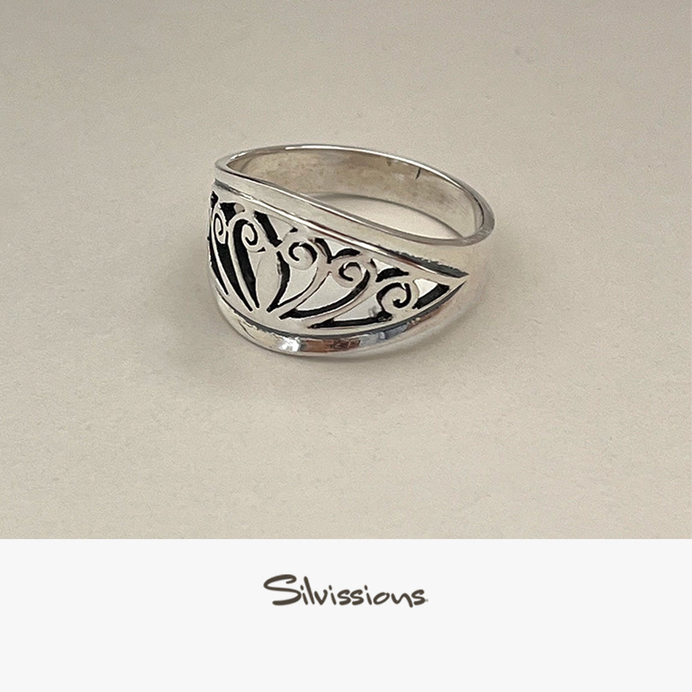 Silver ring with intricate design on a beige background, branded 'Silvissions'.