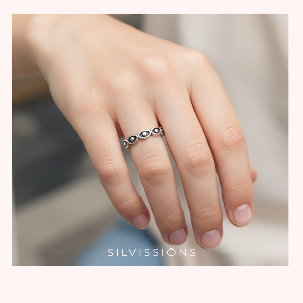 Silver ring on a finger with 'Silvissions' branding