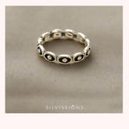 Silver ring with black accents on a beige background, branded 'Silvissions'.