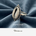 Silver ring with cowrie shell design on a beige background, featuring the brand 'Silvissions'.