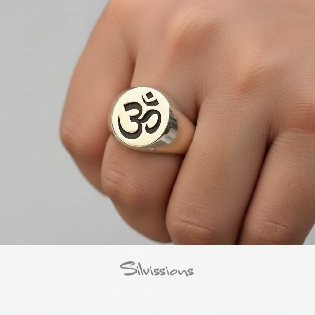 Silver ring with Om symbol on a hand against a neutral background, branded 'Silvissions'.