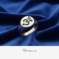 Silver ring with Om symbol on blue fabric, brand 'Silvissions' visible